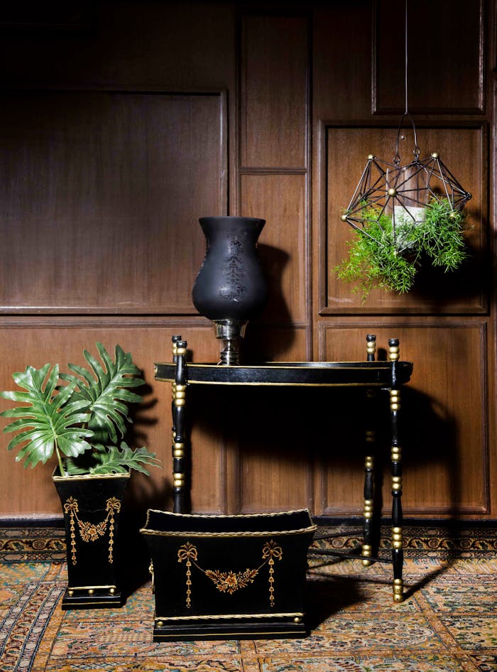 Offerings Sophisticated black and gold furniture and decor set against wood paneling in New Delhi